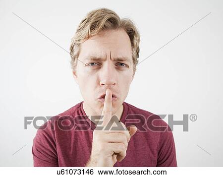 Stock Photograph - Studio Shot of mid adult man with finger on lips. Fotosearch