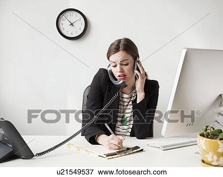 Studio shot of multi-tasking young woman working in office View Large Photo Image Stock Photo - Studio shot of multi-tasking young woman working in office. Fotosearch