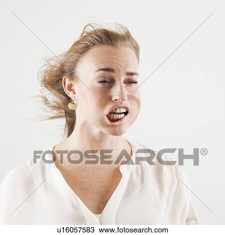 Stock Image - Studio shot of woman with windblown mouth. Fotosearch