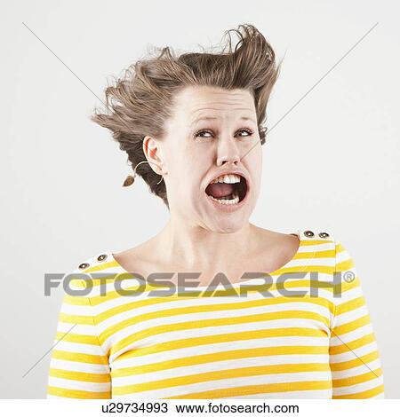 Stock Image - Studio shot of woman with windblown mouth. Fotosearch