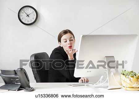 Studio shot of young woman blowing a kiss to computer monitor View Large Photo Image Stock Photograph - Studio shot of young woman blowing a kiss to computer monitor. Fotosearch