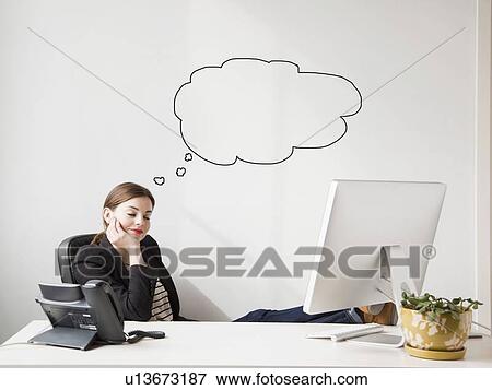 Studio shot of young woman working at desk with thought bubbles next to her head View Large Photo Image Stock Photo - Studio shot of young woman working at desk with thought bubbles next to her head. Fotosearch