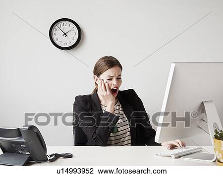 Studio shot of young woman working in office yawning View Large Photo Image Stock Image - Studio shot of young woman working in office yawning. Fotosearch