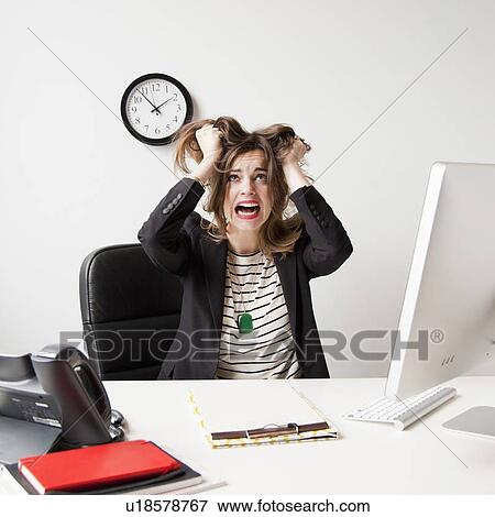 Stock Photo - Studio shot of young woman working in office and tearing her hair out. Fotosearch