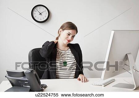 Studio shot of young woman working in office and touching her neck View Large Photo Image Stock Photography - Studio shot of young woman working in office and touching her neck. Fotosearch