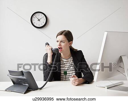 Studio shot of young woman working in office yelling into phone View Large Photo Image Stock Photography - Studio shot of young woman working in office yelling into phone. Fotosearch