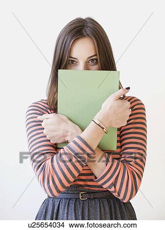Studio shot portrait of young woman holding book View Large Photo Image Picture - Studio shot portrait of young woman holding book. Fotosearch