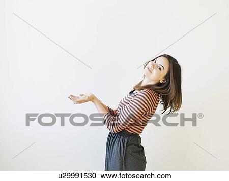 Stock Image - Studio shot young woman bending over backwards pretending like holding something. Fotosearch