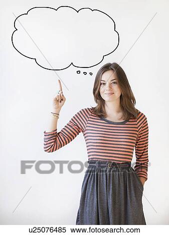 Stock Photography - Studio shot young woman pointing up on thought bubble. Fotosearch