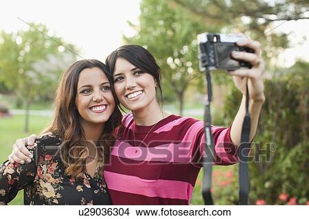 Picture - Two women taking self-portrait picture. Fotosearch