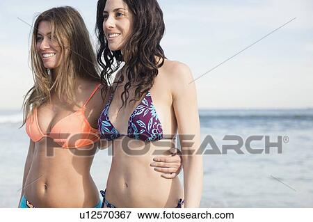 Stock Photo - Two women wearing bikini on beach. Fotosearch