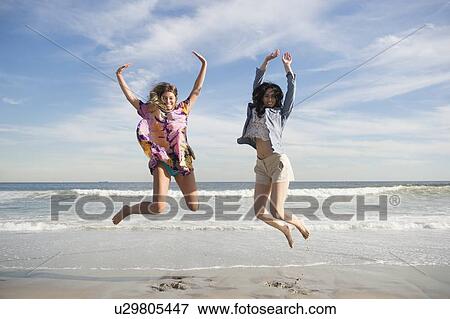Two young women jumping on beach View Large Photo Image Stock Photo - Two young women jumping on beach. Fotosearch