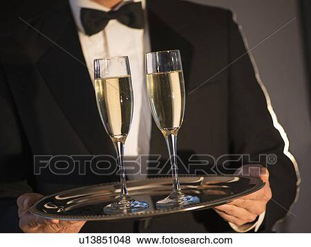 Stock Photo - Waiter holding tray with champagne. Fotosearch
