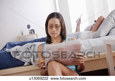 Woman doing crosswords in newspaper and man reading in bed View Large Photo Image Stock Image - Woman doing crosswords in newspaper and man reading in bed. Fotosearch