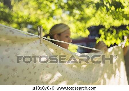 Woman hanging laundry on clothesline View Large Photo Image Stock Photograph - Woman hanging laundry on clothesline. Fotosearch