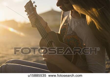 Woman playing ukulele at sunset View Large Photo Image Stock Photography - Woman playing ukulele at sunset. Fotosearch