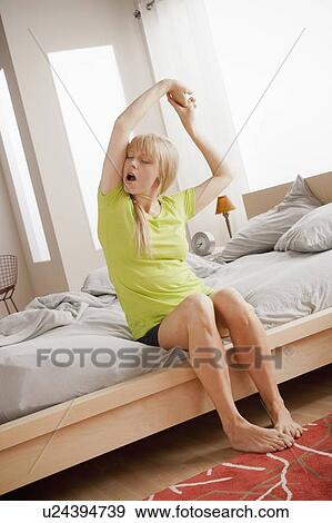 Woman sitting on bed, yawning and stretching View Large Photo Image Stock Photo - Woman sitting on bed, yawning and stretching. Fotosearch