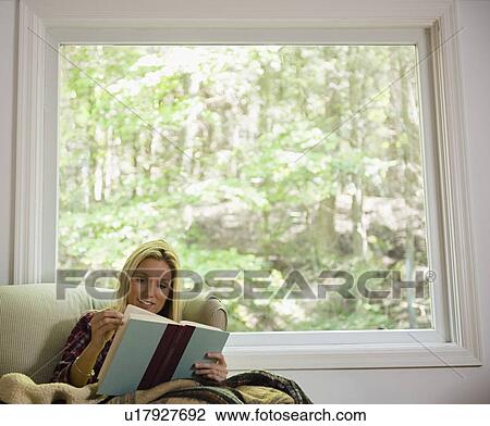 Woman sitting on sofa and reading book View Large Photo Image Stock Image - Woman sitting on sofa and reading book. Fotosearch
