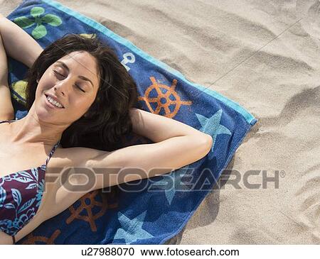 Stock Image - Woman sunbathing at beach. Fotosearch