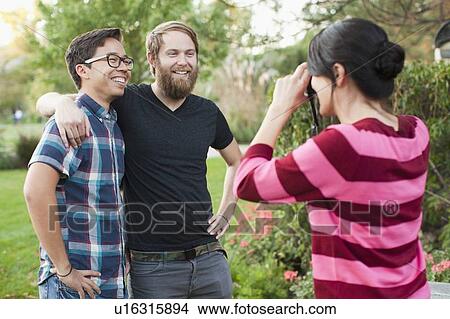 Woman taking picture of two male friends View Large Photo Image Picture - Woman taking picture of two male friends. Fotosearch