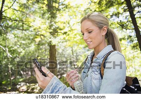 Stock Photo - Woman using cell phone in forest. Fotosearch