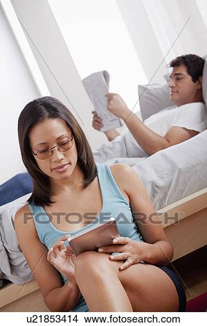 Woman using digital tablet and man reading newspaper View Large Photo Image Picture - Woman using digital tablet and man reading newspaper. Fotosearch