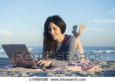 Stock Photograph - Woman using laptop on beach. Fotosearch