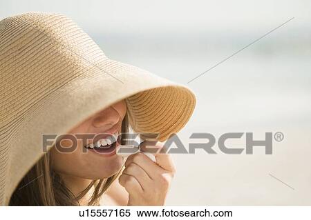 Woman wearing sun hat applying lipstick View Large Photo Image Stock Photography - Woman wearing sun hat applying lipstick. Fotosearch