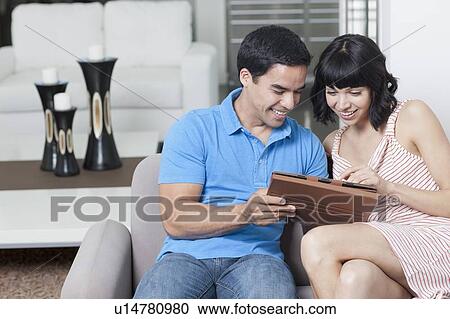 Young couple looking at photos View Large Photo Image Stock Image - Young couple looking at photos. Fotosearch