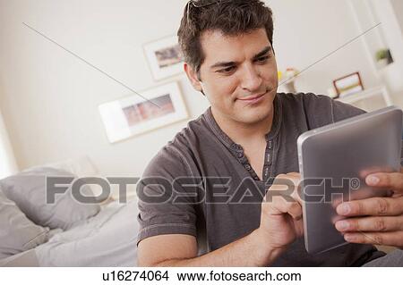 Young man using digital tablet View Large Photo Image Picture - Young man using digital tablet. Fotosearch