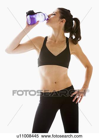 Young woman drinking water after exercising, studio shot View Large Photo Image Stock Photography - Young woman drinking water after exercising, studio shot. Fotosearch