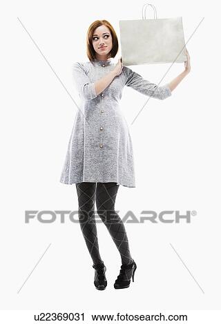 Young woman holding shopping bag, studio shot View Large Photo Image Stock Image - Young woman holding shopping bag, studio shot. Fotosearch