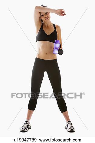 Stock Photo - Young woman resting after exercising, studio shot. Fotosearch