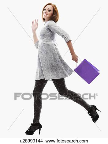 Young woman running with shopping bag, studio shot View Large Photo Image Picture - Young woman running with shopping bag, studio shot. Fotosearch