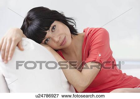 Stock Photo - Young woman sitting on sofa. Fotosearch