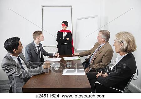 Business leader as superhero in front of colleagues at meeting in conference room View Large Photo Image Picture - Business leader as superhero in front of colleagues at meeting in conference room. Fotosearch
