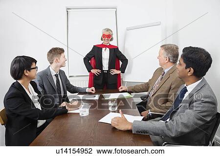 Business leader as superhero in front of colleagues at meeting in conference room View Large Photo Image Stock Image - Business leader as superhero in front of colleagues at meeting in conference room. Fotosearch