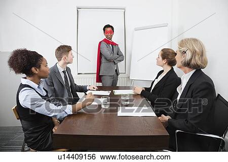 Business leader as superhero in front of colleagues at meeting in conference room View Large Photo Image Stock Photograph - Business leader as superhero in front of colleagues at meeting in conference room. Fotosearch