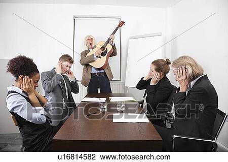 Stock Image - Businessman playing guitar in business meeting. Fotosearch