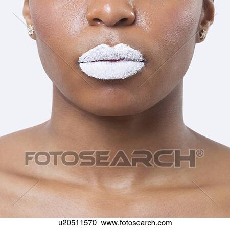 Stock Image - Close-up shot of young African American woman with white lips over white background. Fotosearch
