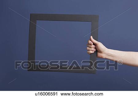Stock Image - Hand holding frame over blue background. Fotosearch