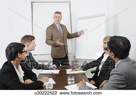 Stock Image - Man using whiteboard in business meeting. Fotosearch