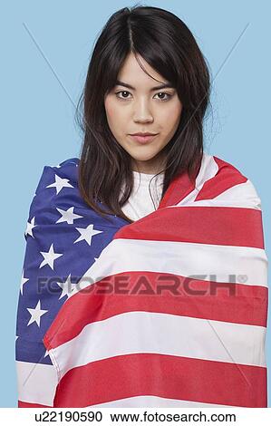 Patriotic young woman wrapped in American flag over blue background View Large Photo Image Stock Image - Patriotic young woman wrapped in American flag over blue background. Fotosearch