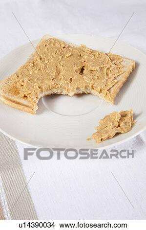 Picture - Peanut butter on slice of bitten bread. Fotosearch