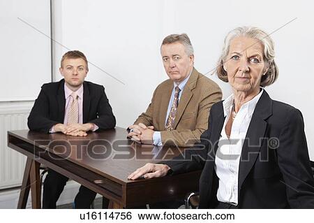 Stock Photograph - Portrait of confident business group at desk in office. Fotosearch