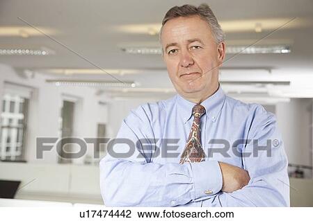 Stock Image - Portrait of confident businessman with arms crossed in office. Fotosearch