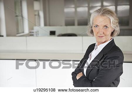 Stock Photo - Portrait of confident senior businesswoman with arms crossed in office. Fotosearch