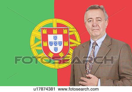 Stock Image - Portrait of middle-aged businessman standing over Portuguese flag. Fotosearch