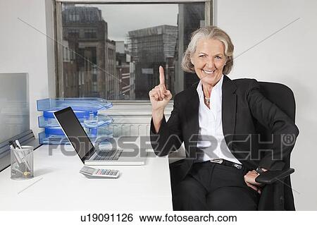 Portrait of senior businesswoman with laptop at desk in office View Large Photo Image Stock Photograph - Portrait of senior businesswoman with laptop at desk in office. Fotosearch