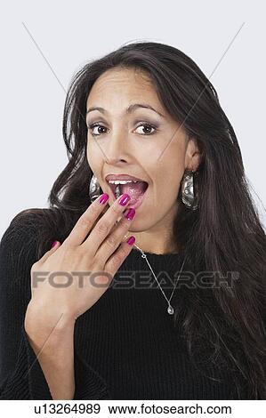 Portrait of surprised happy young woman with hand over mouth against white background View Large Photo Image Stock Photo - Portrait of surprised happy young woman with hand over mouth against white background. Fotosearch